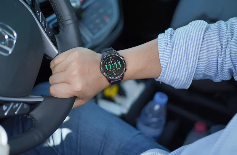 Homem dirigindo, no braço direito relógio exibindo 11:11 - significado das horas iguais